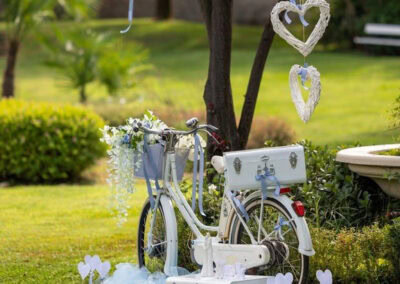 Decorazione romantica con bici, cuori e ombrello in un giardino verde.
