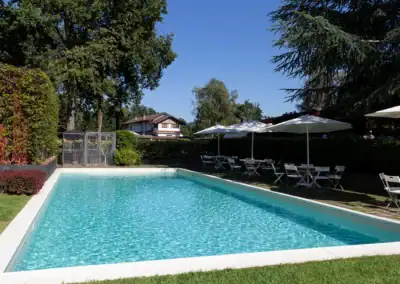 Piscina esterna con ombrelloni e sedie, ideale per eventi e relax all'aperto.