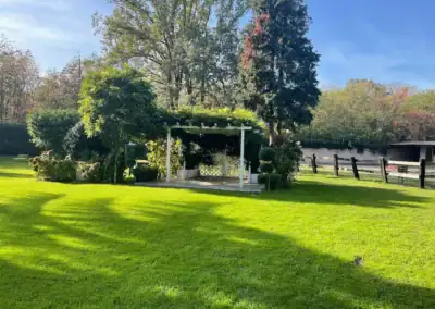 Gazebo nel giardino con vegetazione rigogliosa, ideale per eventi e cerimonie all'aperto.